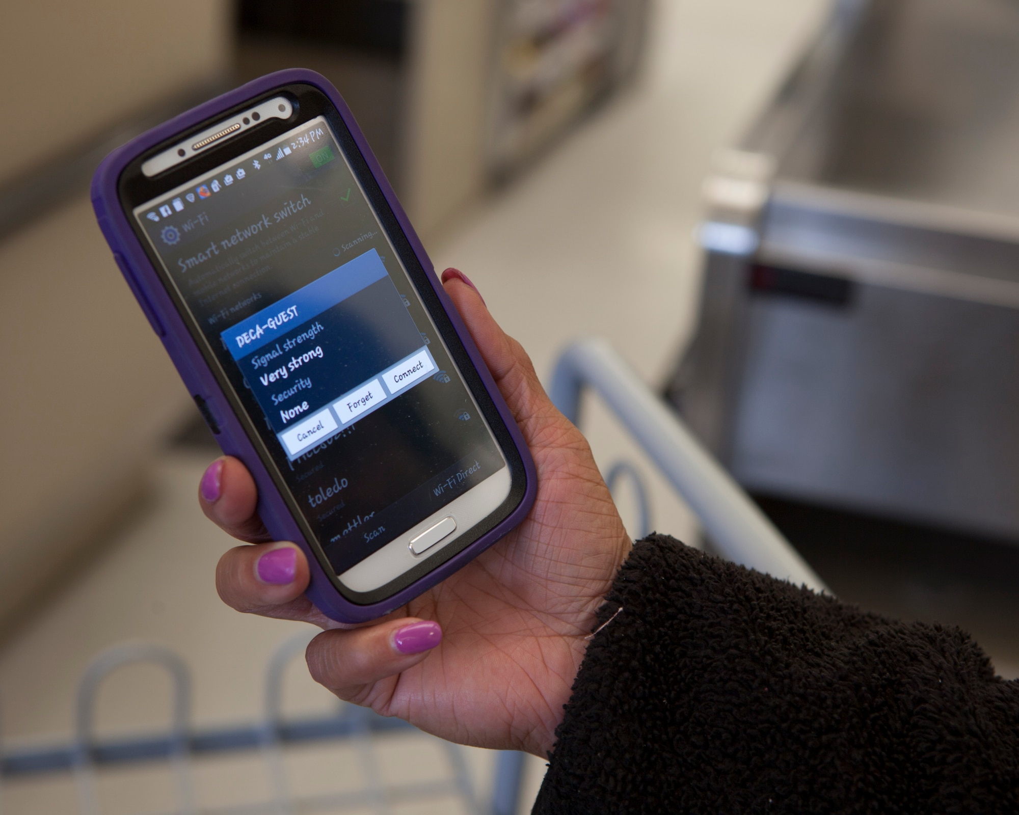 An F.E. Warren Commissary employee observes the Wi-Fi prompt on her smart phone on F.E. Warren Air Force Base, Wyo., April 23, 2015. The commissary activated its in-store Wi-Fi through the Defense Commissary Agency's Commissary Patron Internet Mobile System. (U.S. Air Force photo by Lan Kim)