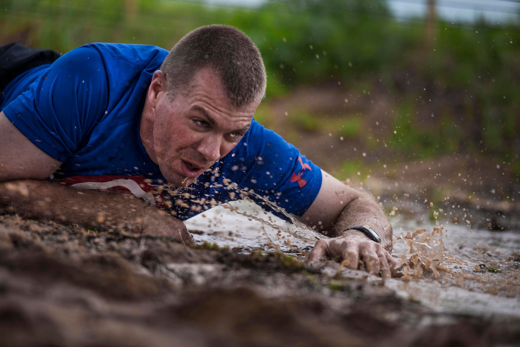 U.S. Air Force Capt. Joshua Meyer, 363rd Training Squadron logistics readiness officer training instructor, crawls through a muddy obstacle during the Sheppard Air Force Base, Texas, Combat Barbeque 5k run. The Air Force ensures Airmen are ready for new missions by holding morale events that bring the community together in a family setting to strengthen mental, physical, social and spiritual fitness. (U.S. Air Force photo by Senior Airman Kyle Gese/Released)