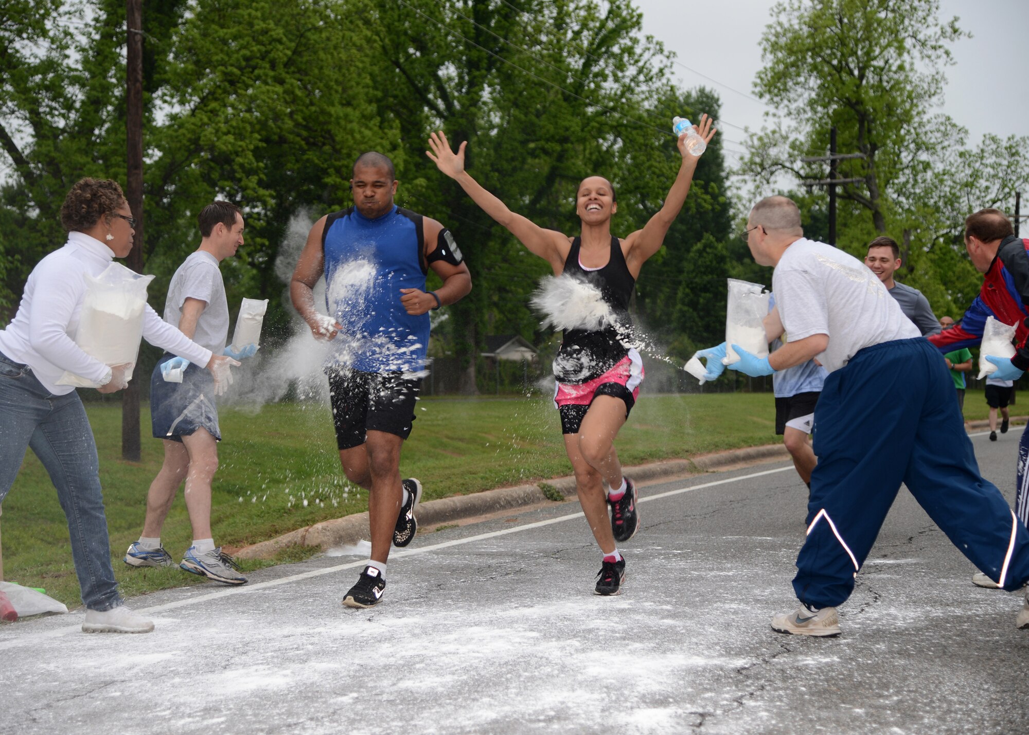 Participants of the Color Me Run have white chalk thrown at them on Barksdale Air Force Base, La., April 24, 2015. The white chalk represents chaplain and Airman and Family Readiness Center Airmen, and is also one of five helping agencies that took part in the 5k event. (U.S. Air Force photo/Senior Airman Joseph A. Pagán Jr.)
