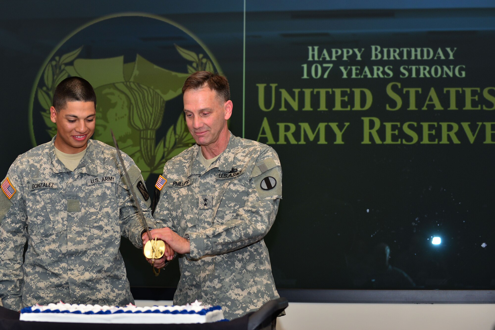 U.S. Army Maj. Gen. Jeffrey E. Phillips, U.S. Army Reserve deputy commander, right, cuts the U.S. Army Reserve birthday cake with Private 1st Class Jose Gonzales, 1st-1222 Bravo Company Aviation Regiment avionic mechanic, at U.S. Army Training and Doctrine Command on Fort Eustis, Va., April 23, 2015. Gonzales was selected as the youngest Army Reserve Soldier in the local area to cut the cake with the General. (U.S. Air Force photo by Staff Sgt. Natasha Stannard/Released) 