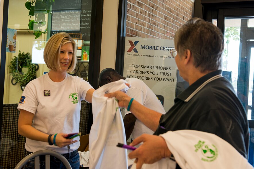 Lori Burnam, 23d Civil Engineer Squadron environmental, gives out Earth Day T-Shirts at the Base Exchange April 22, 2015, at Moody Air Force Base, Ga. Moody celebrated Earth Day to help the recycling initiative and improve the base’s environment. (U.S. Air Force photo by Airman 1st Class Dillian Bamman/Released)