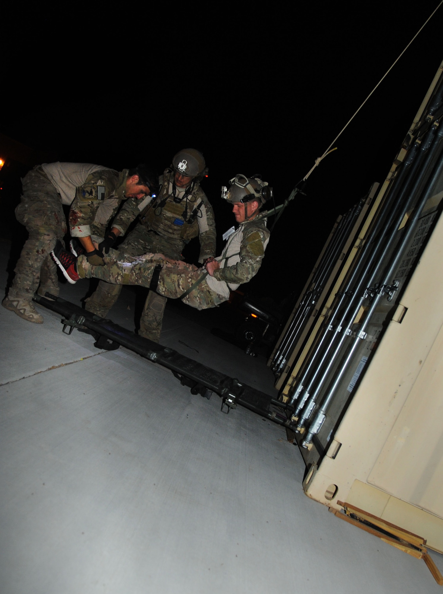 U.S. Air Force Pararescuemen, 48th Rescue Squadron, position a simulated patient on a gurney while the patient is lowered from the top of a conex during a pre-deployment training exercise at Davis-Monthan Air Force Base, Ariz., April 14, 2015. The exercise focused on mass casualty treatment, evacuation, extrication, confined space and collapsed structure rescue.  (U.S. Air Force photo by Senior Airman Betty R. Chevalier)