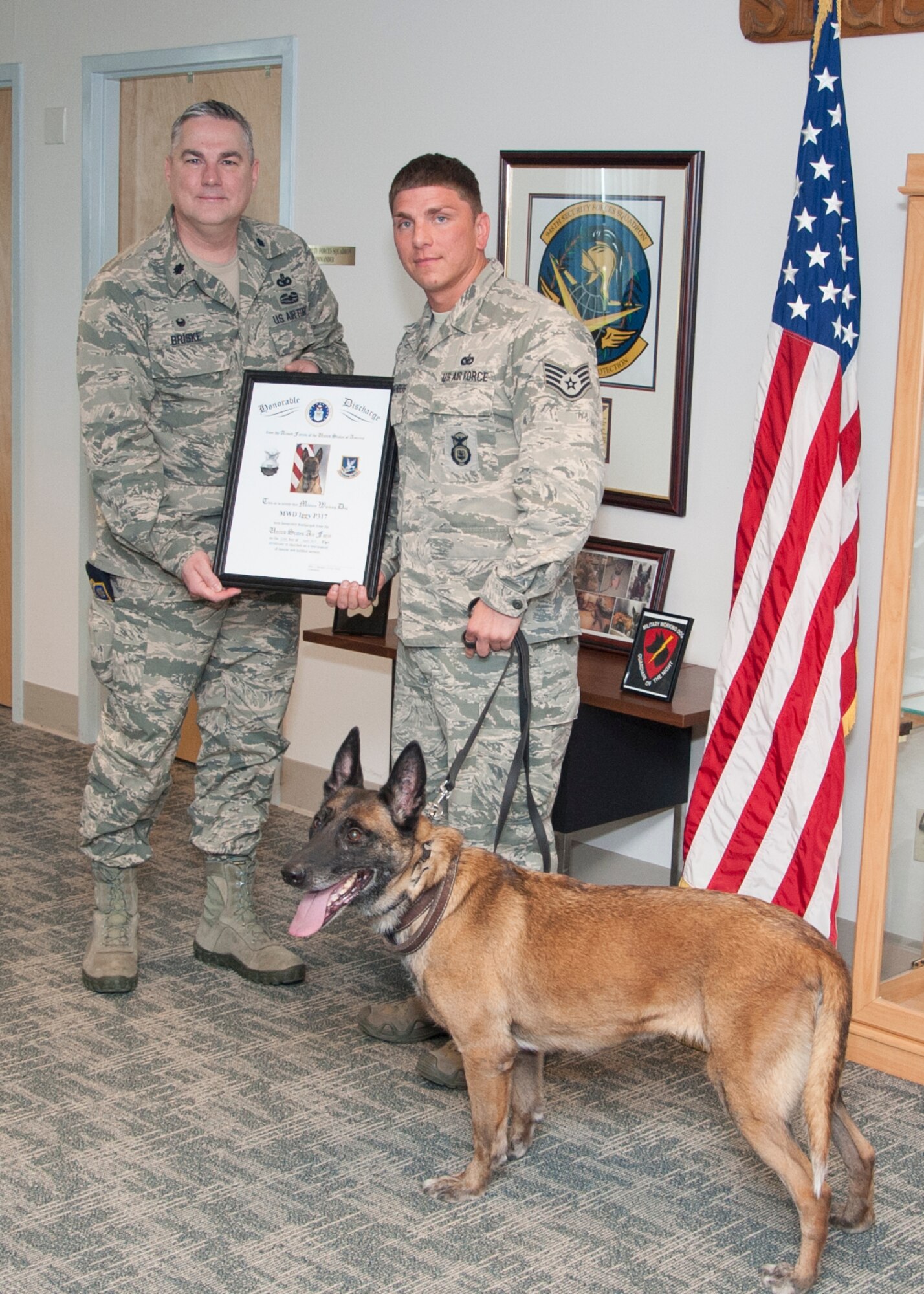 Lt. Col. Joel Briske, 436th Security Forces Squadron commander, presents Staff Sgt. Jason Spangenberg, 436th SFS military working dog handler, with Iggy’s, 436th SFS MWD, discharge certificate during her retirement ceremony April 22, 2015, at Dover Air Force Base, Del. Iggy was born April 1, 2008 and entered the United States Air Force April 21, 2010. (U.S. Air Force photo/Senior Airman Jared Duhon)