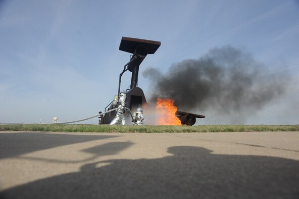 Firefighters of the 509th Civil Engineer Squadron execute coordinated movements and use teamwork to extinguish flames during a fire pit training exercise at Whiteman Air Force Base, Mo. April 2, 2015. The exercise uses controlled burns to simulate conditions of a real-world crash site. (U.S. Air Force photo by Airman 1st Class Jovan Banks/Released)
