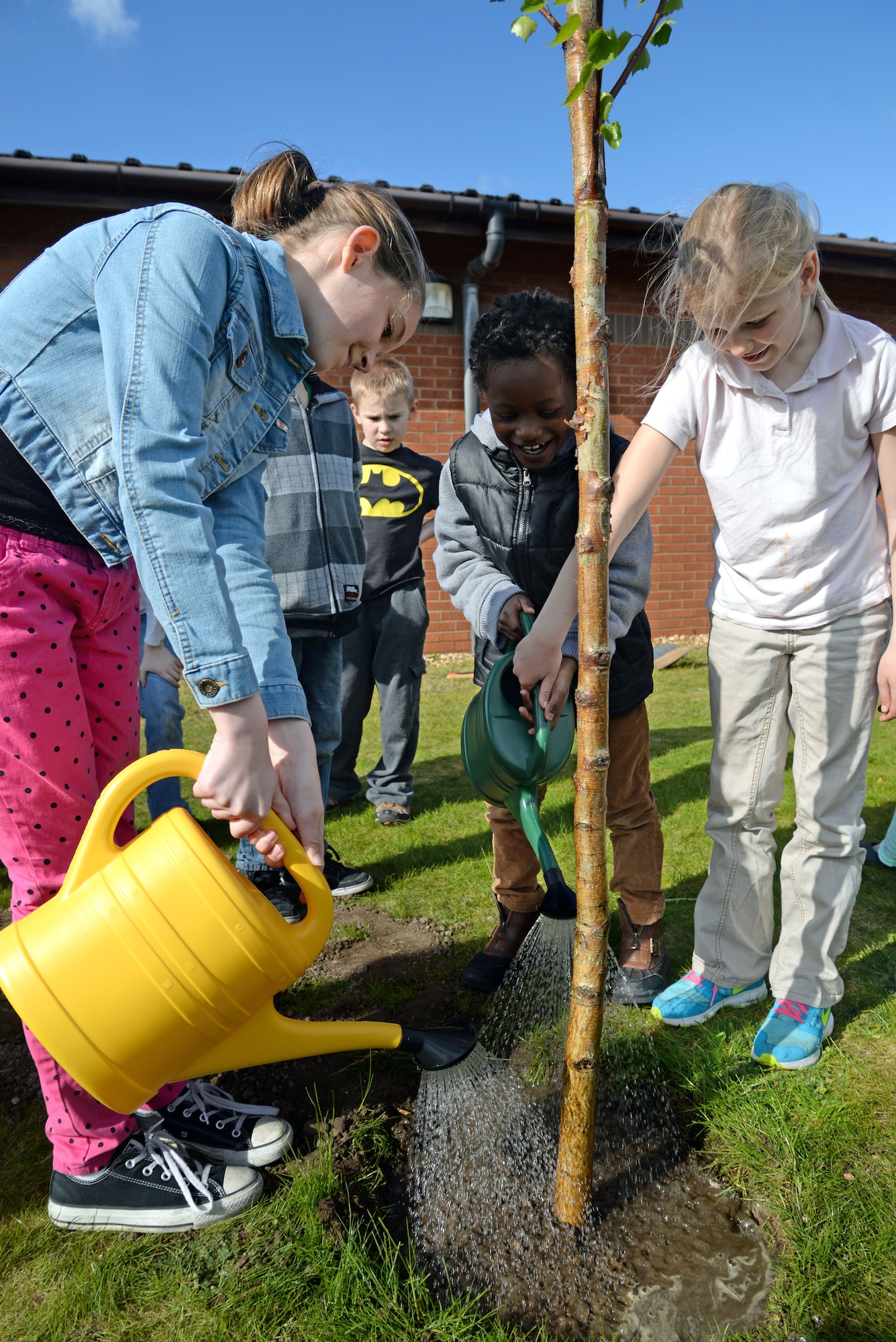 Children from the RAF Mildenhall Youth Center water a newly planted tree as part of Earth Day April 22, 2015, on RAF Mildenhall, England. Planting a tree is one of many activities provided on base for Earth Week. (U.S. Air Force photo by Senior Airman Christine Halan/Released)