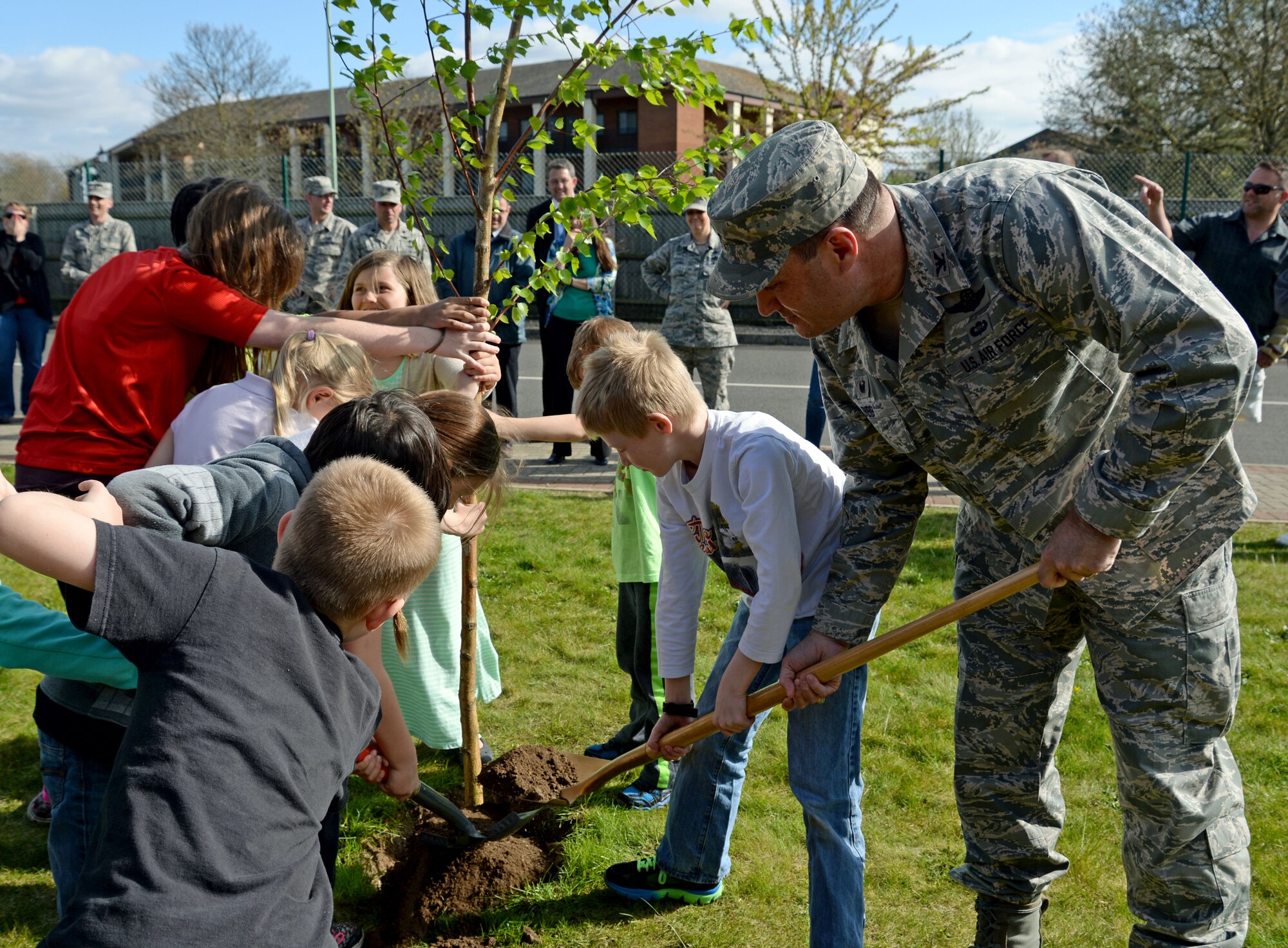 Children from the RAF Mildenhall Youth Center help U.S. Air Force Col. Kenneth T. Bibb, Jr., 100th Air Refueling Wing commander, plant a tree April 22, 2015, on RAF Mildenhall, England. Planting a tree is one of many activities held on base for Earth Week. Earth Week is held Air Force-wide on an annual basis to promote helping the environment. (U.S. Air Force photo by Senior Airman Christine Halan/Released)