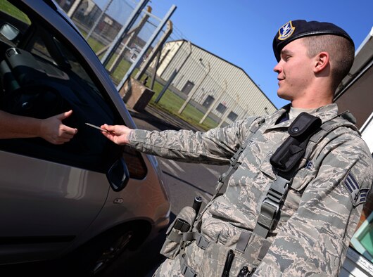 U.S. Air Force Senior Airman Jonathan T. Mamott, 100th Security Forces Squadron response force leader from Cape Coral, Fla., hands back a control access card to a base member April 23, 2015, on RAF Mildenhall, England. Mamott was awarded the Square D Spotlight for displaying the core value of Excellence in All We Do. (U.S. Air Force photo by Senior Airman Christine Halan/Released)