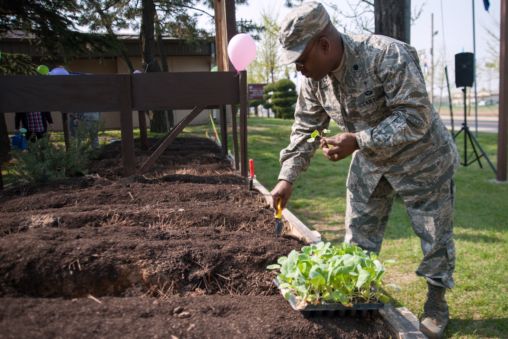 Lt. Col. Dwayne “Shepherd” Jones, 8th Fighter Wing chaplain, gives some planting tips to Airmen while planting lettuce seedlings in the Wolf Pack Garden in observance of Earth at Kunsan Air Base, Republic of Korea, April 22, 2015. The garden project started March 14 as part of a community initiative to promote healthy living for Wolf Pack Airmen. (U.S. Air Force photo by Tech. Sgt. George Maddon/Released)