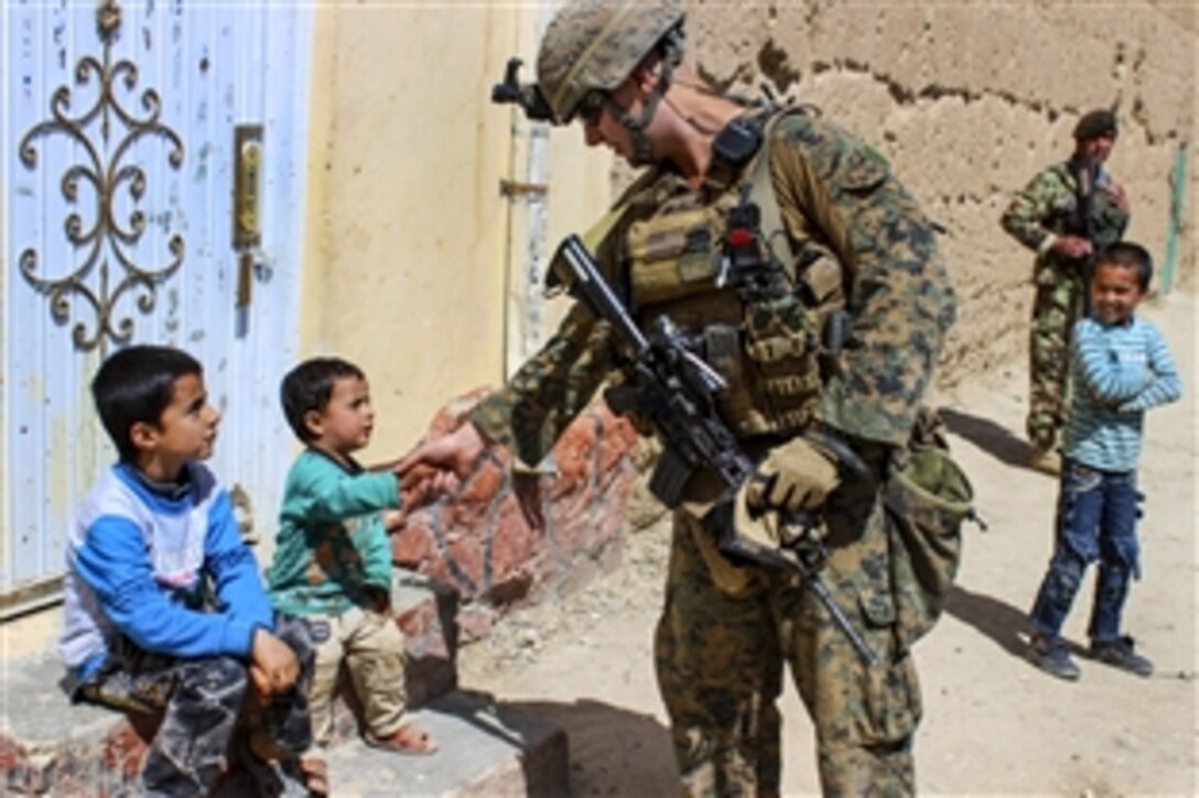 A U.S. Marine shakes hands with an Afghan child while on patrol near Bagram Airfield, Afghanistan, April 6, 2015. The Marine is assigned to the Georgian Deployment Program.