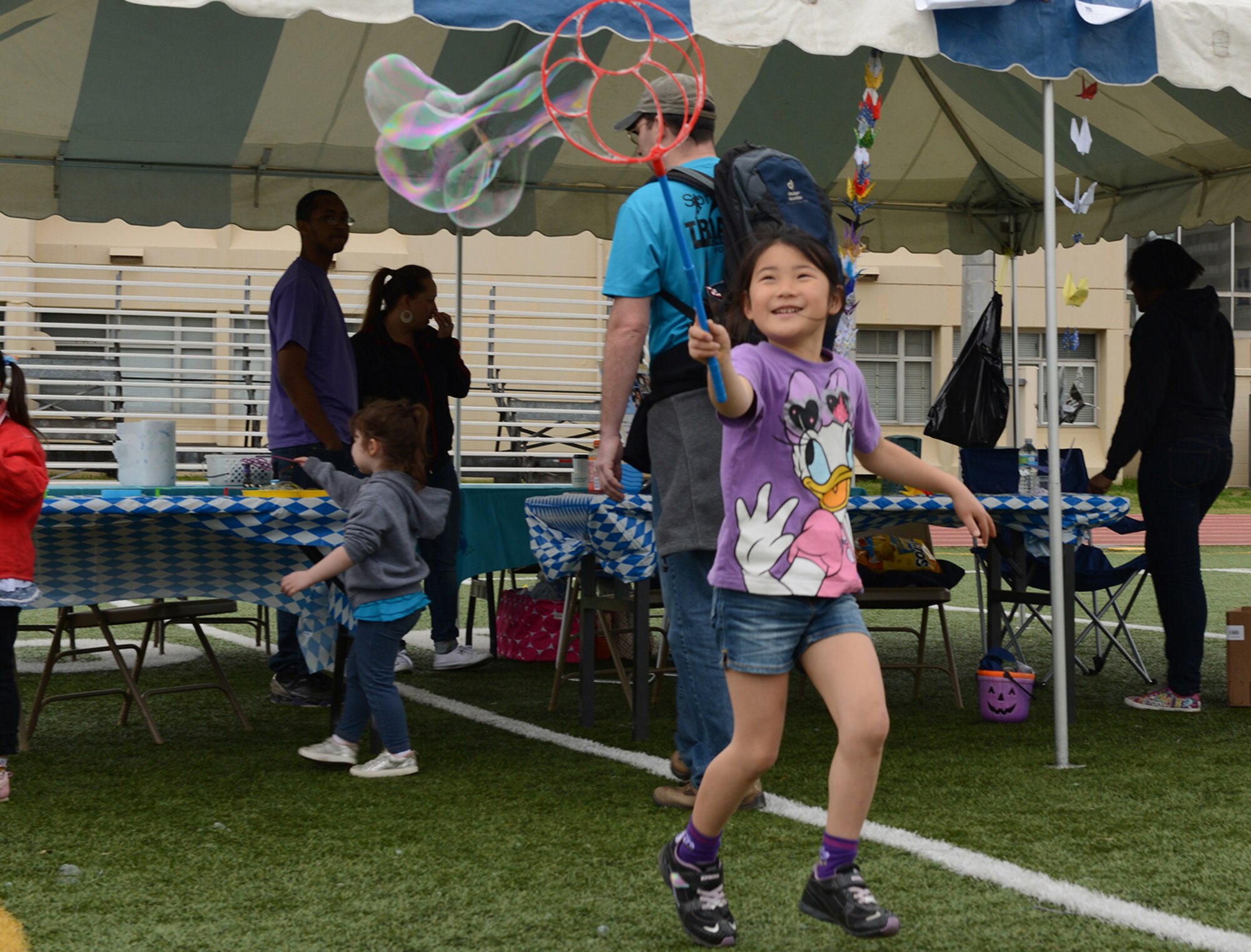 A child runs with a bubble wand during the Youth Festival at Yokota Air Base, Japan, April 19, 2015. The Youth Festival was a celebration for the month of the military child and honored those children, which make up the Yokota community. (U.S. Air Force photo by Senior Airman Desiree Economides/Released)
