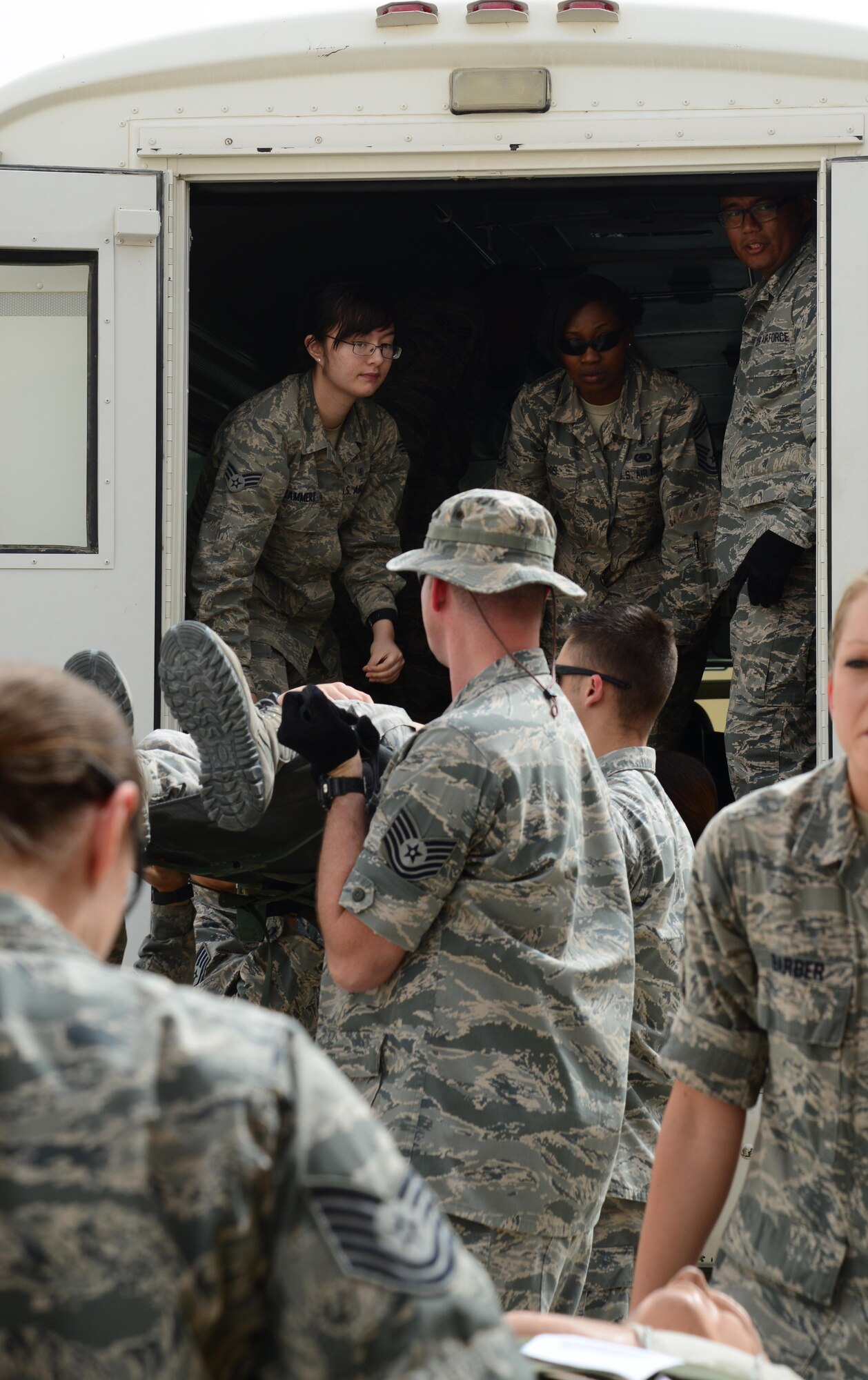 Airmen from the 379th Expeditionary Medical Group unload patients from an ambulatory bus during a Major Accident Response Exercise, April 22, 2015, at Al Udeid Air Base, Qatar. The MARE, which is a mission assurance exercise is required by all Department of Defense Bases on an annual cycle, ensures that personnel are properly trained and proficient at responding to incidents or threats in the event of a real world occurrence. (U.S. Air Force photo by Senior Airman Kia Atkins)