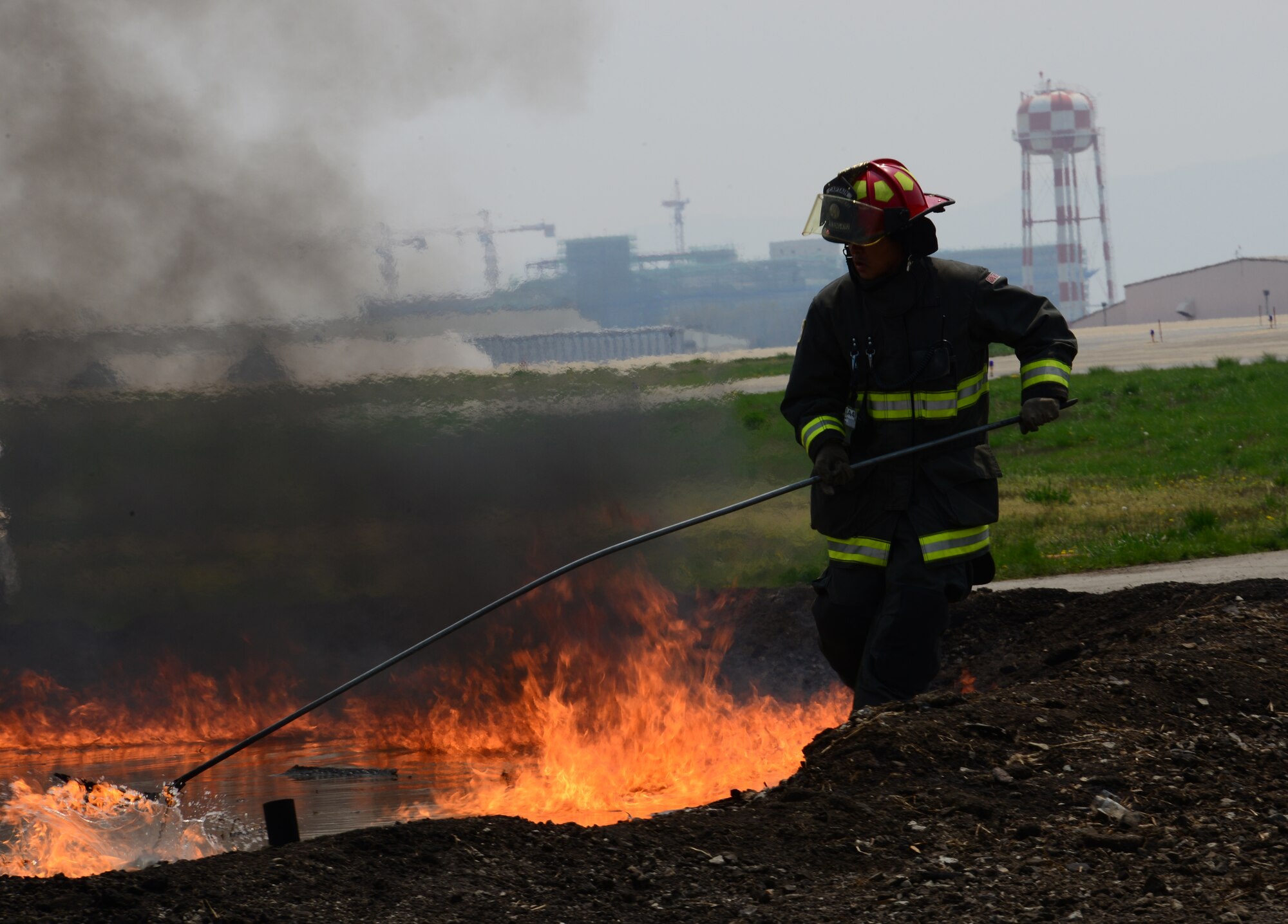 A fire fighter assigned to the U.S. Army Garrison Humphreys', Republic of Korea, lights the pit fire for firefighters from Osan Air Base, ROK, April 22, 2015. Firefighters teamed up for structural training in order to stay proficient in their tasks. (U.S. Air Force photo by Senior Airman Benjamin Sutton/Released)