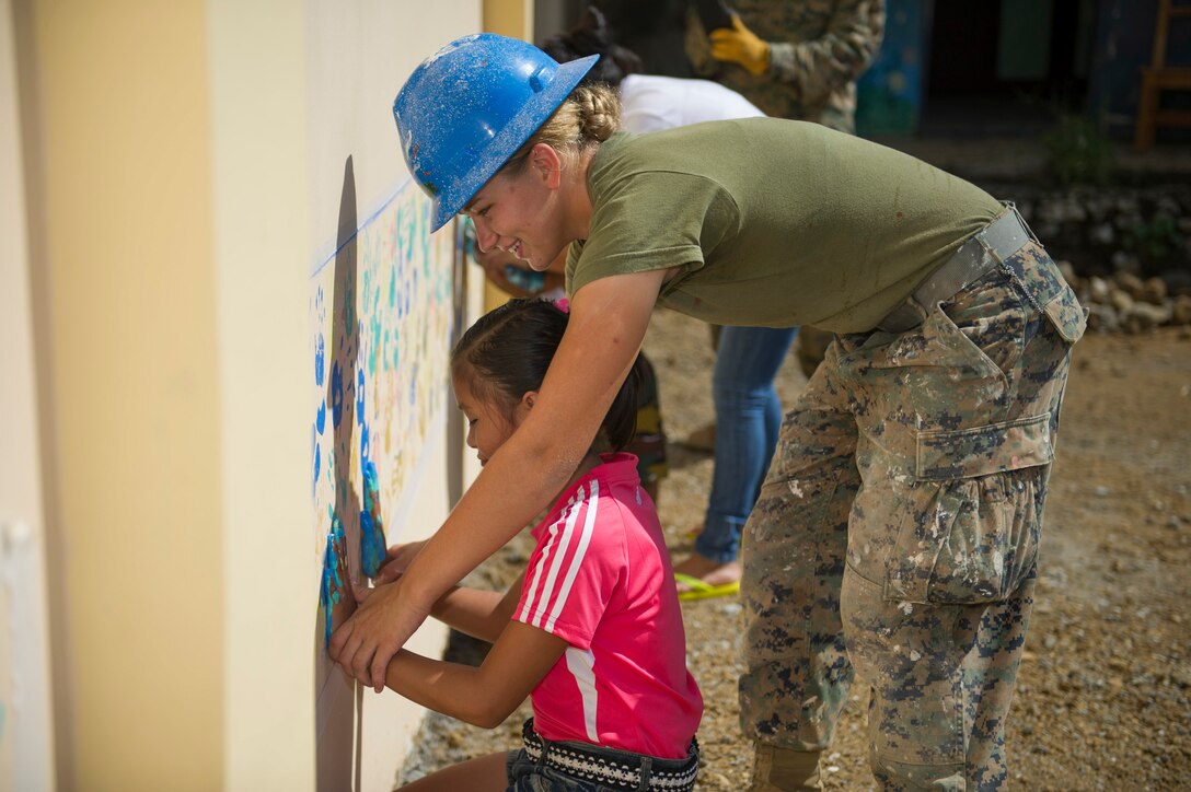 TAPAZ, Philippines — U.S. Marine Lance Cpl. Dana Deline, assigned to the 9th Engineer Support Battalion, helps a schoolchild to paint her palm prints on a wall for a mural on a new school building at Don Joaquin Artuz Memorial Elementary School in Tapaz, Philippines, during Balikatan 2015, April 25. The two-classroom building is being constructed by U.S. Marine, Navy, and Armed Forces of the Philippines Army engineers as part of the Combined-Joint Civil-Military Operations Task Force on the island of Panay. Balikatan, which means “shoulder to shoulder” in Filipino, is an annual bilateral training exercise aimed at improving the ability of Philippine and U.S. military forces to work together during planning, humanitarian assistance and disaster relief operations.