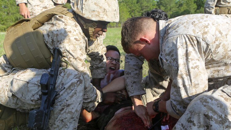 Navy corpsmen with 2nd Medical Battalion apply a tourniquet to a simulated blast patient before bringing him into the medical trauma treatment tent during a field training exercise aboard Camp Lejeune, N.C., April 23, 2015. The purpose of the exercise was to train and prepare supplemental Health Services Augmented Personnel for deployment to exercises African and Eager Lion.