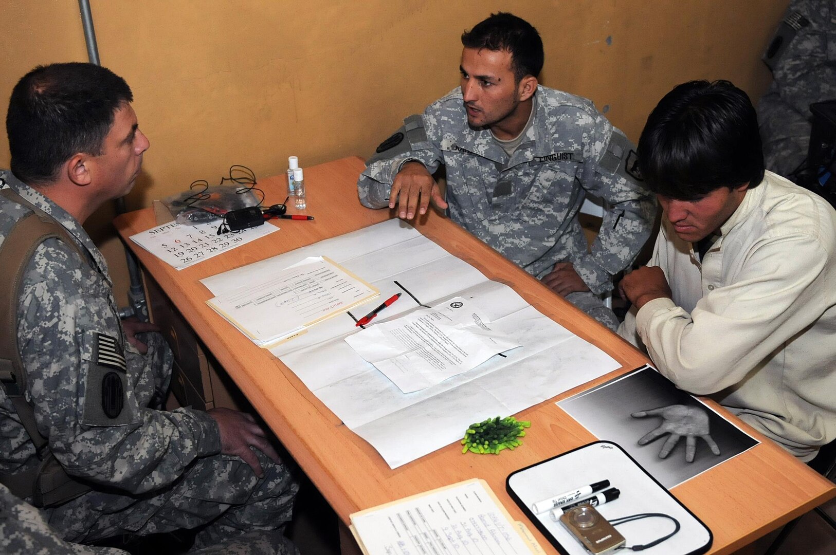 Lt. Col. Donald McCarty, left, deputy staff judge advocate for the 196th Maneuver Enhancement Brigade of the South Dakota Army National Guard listens as Rahim, center, a linguist for the 196th, explains a claim made by Naqeb, right, a local Afghan citizen. McCarty helps local Afghans file claims against the U.S. military when any incident, such as a car accident happens.
