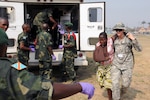 Spc. Kerry Thompson of Bismarck, N.D., a combat medic with the North Dakota National Guard's 814th Army Support Medical Company, carries a simulated injured patient to the hands of an Armed Forces of the Democratic Republic of the Congo soldierin Kinshasa, Democratic Republic of the Congo, Sept. 17, 2010. A mass casualty exercise simulated a bus crash with about 50 patients that were treated by the FARDC quick reaction force. 