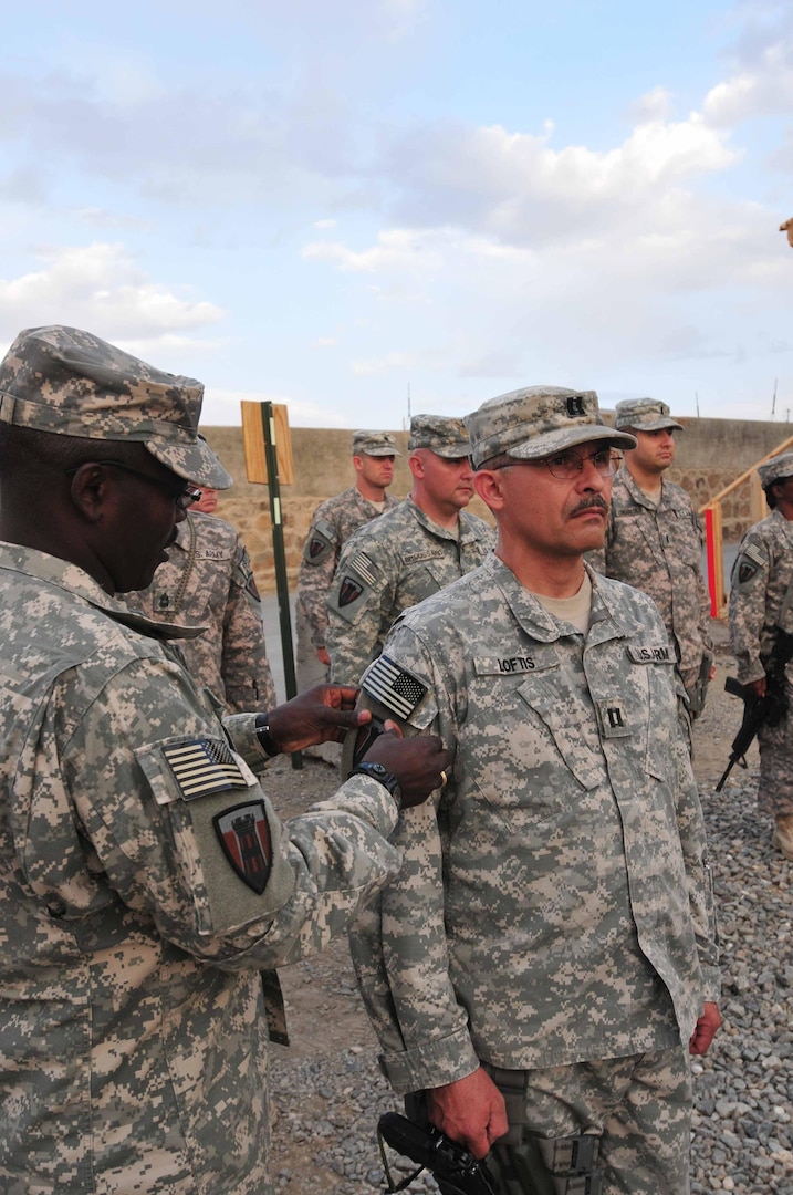 Army Brig. Gen. Lester Simpson, commander of the Texas Army National Guard's 176th Engineer Brigade, places a combat patch on the right sleeve of Army Capt. Thomas Loftis, commander of the brigade's Headquarters and Headquarters Company, at a ceremony on Forward Operating Base Sharana Sept. 11, 2010.