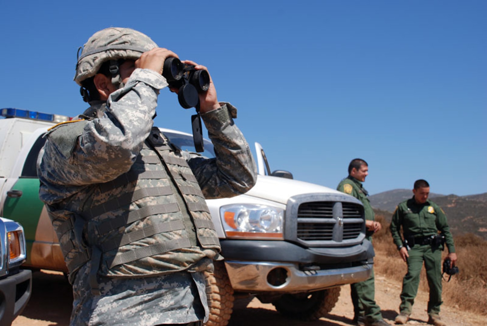 A California National Guard Soldier, left, works with U.S. Customs and Border Protection agents to scour the hills near the U.S.-Mexico border.