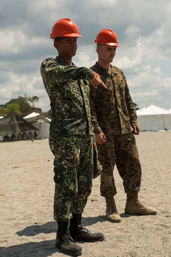 Philippine Marine Pvt. Mark T. Ferranco and U.S. Marine Cpl. Lorin E. Newham use hand and arm signals to safely guide a 20-ton container at Crow Valley, Philippines, April 23 during Exercise Balikatan 2015. Philippine Marines worked with their U.S. counterparts to learn the capabilities of the AMK-36 and the MKR-15 wrecker logistical vehicles. The vehicles are logistical assets that Marines use to enhance the Marine Corps’ expeditionary nature. The Philippine Marines learned how the U.S. Marines use their vehicles during recovery missions and port operations. Balikatan is an annual exercise that enhance military-to-military relationships with the Armed Forces of the Philippines. Cooper is a wrecker chief currently assigned to Combat Logistics Battalion 4, Combat Logistics Regiment 3, 3rd Marine Logistics Group, III Marine Expeditionary Force. Ferranco is a motor transportation operator assigned to Motor Transportation and Maintenance Battalion, Service Support Brigade.