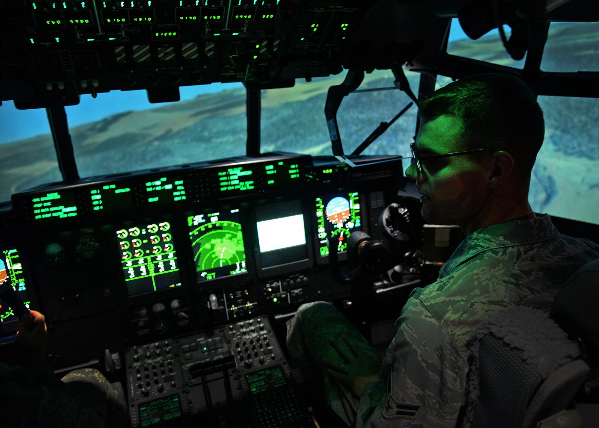 U.S. Air Force Airman 1st Class Nathanael Meyr, 27th Special Operations Wing executive services, receives instructions before taking control of the MC-130 J Commando II simulator during a tour April 21, 2015 at Cannon Air Force Base, N.M. This tour gave airmen who would not normally have the opportunity to get hands-on experience with the simulators or who have career fields that limit access to Cannon’s aircraft, an inside look as to what is required of Cannon’s pilots. (U.S. Air Force photo/Airman 1st Class Chip Slack)