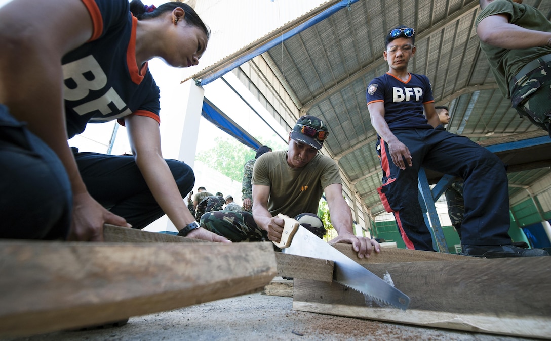 Armed Forces of the Philippines Cpl. Gary Kutat, left, 408th Community Defense Center driver, cuts lumber during the construction of a split sole rakers and T-spots as part of exercise Balikatan’s urban search and rescue training in Puerto Princesa City, Palawan, Philippines, April 24. The USAR training familiarized BK15 participants in lumber cutting and basic shoring, enabling them to more effectively construct T-spots and split soles in case a collapsing building needs to be supported during a real world mission. This year marks the 31st iteration of the exercise, which is an annual Philippines-U.S. bilateral military training exercise and humanitarian civic assistance engagement.