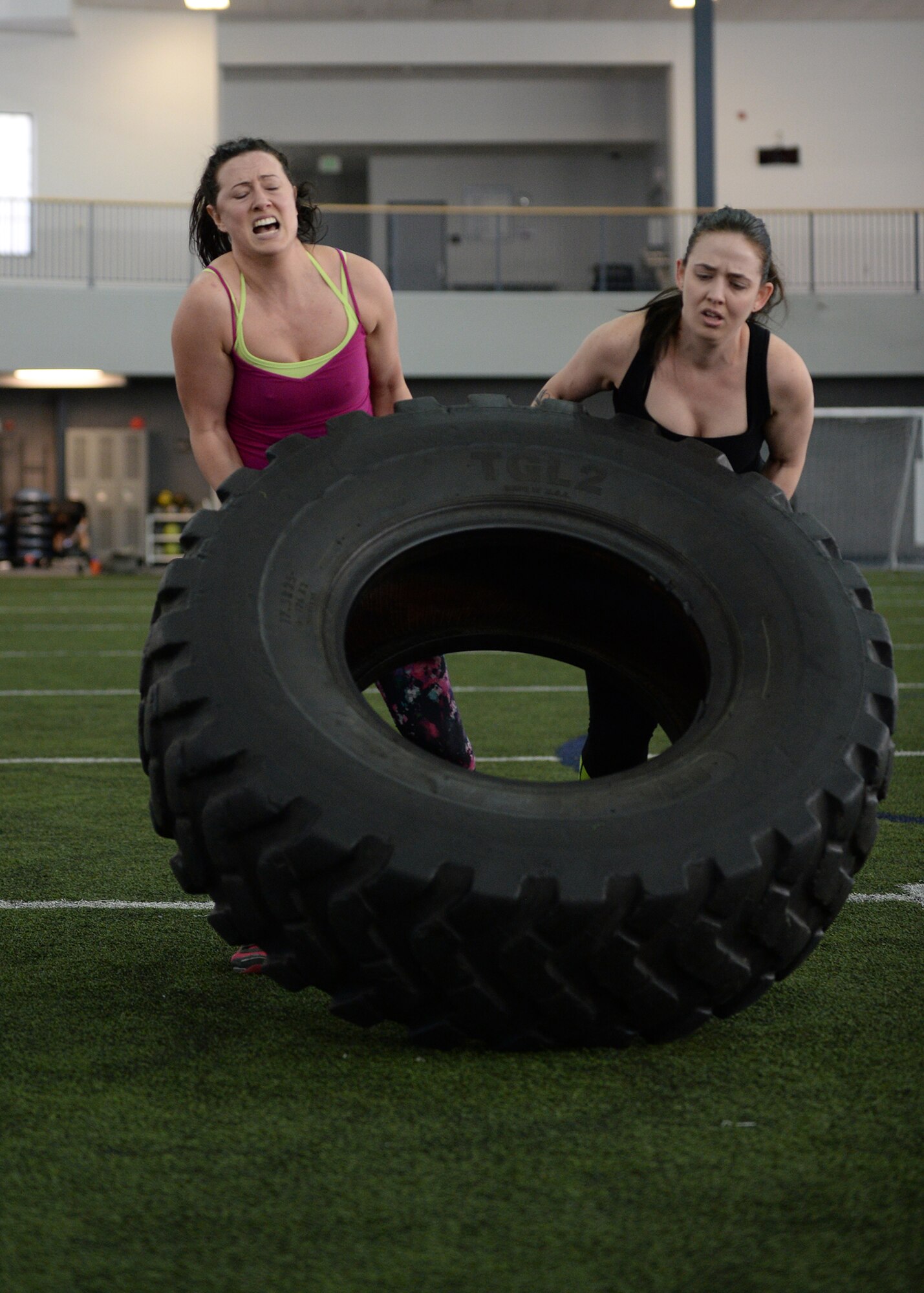 Amber Ortman (left), wife of U.S. Air Force Master Sgt. Marcus Ortman, the 354th Logistics Readiness Squadron fuels section chief, and Kristen Crush, a University of Alaska Anchorage nursing student, flip a tire during the “Tough Enough” competition April 24, 2015, at the Baker Field House on Eielson Air Force Base, Alaska. The “Tough Enough” competition was a series of strength-based exercises to promote sexual assault awareness and prevention while introducing knowledge on the subject. (U.S. Air Force photo by Staff Sgt. Shawn Nickel/Released)