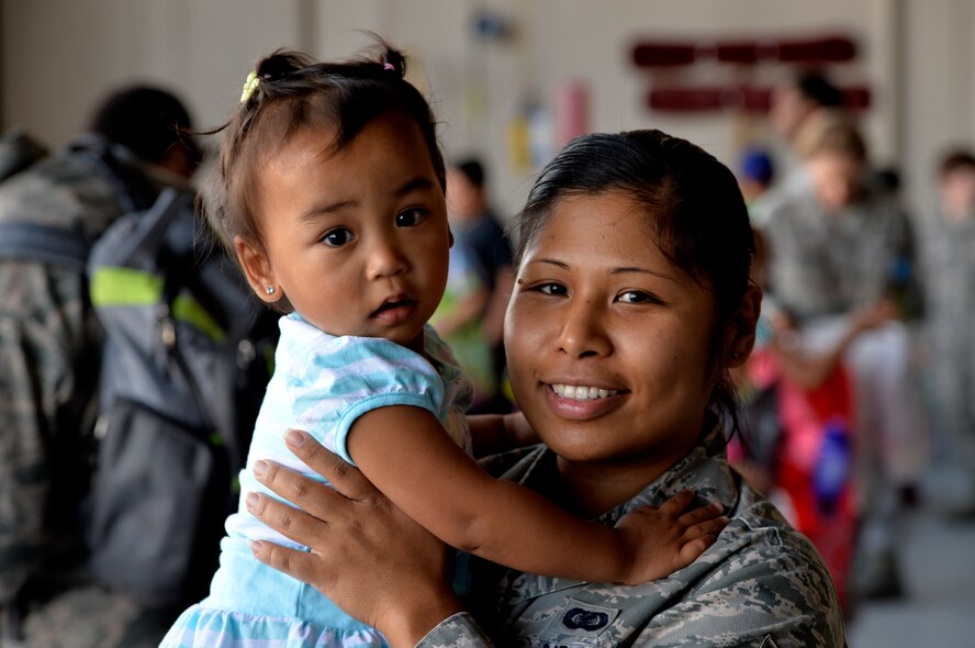 Staff Sgt. Krizia Valenzuela, 432nd Wing executive administration, and her daughter Ahrie, pose for a photo during “Take Your Kid to Work Day” April 23, 2015.  During the day's events the Creech Airmen and various base and local organizations provided a plethora of events including demonstrations from the local fire department, work center tours, a professional magician, and a DJ. (U.S. Air Force photo by Senior Airman Adairus Petty/Released)