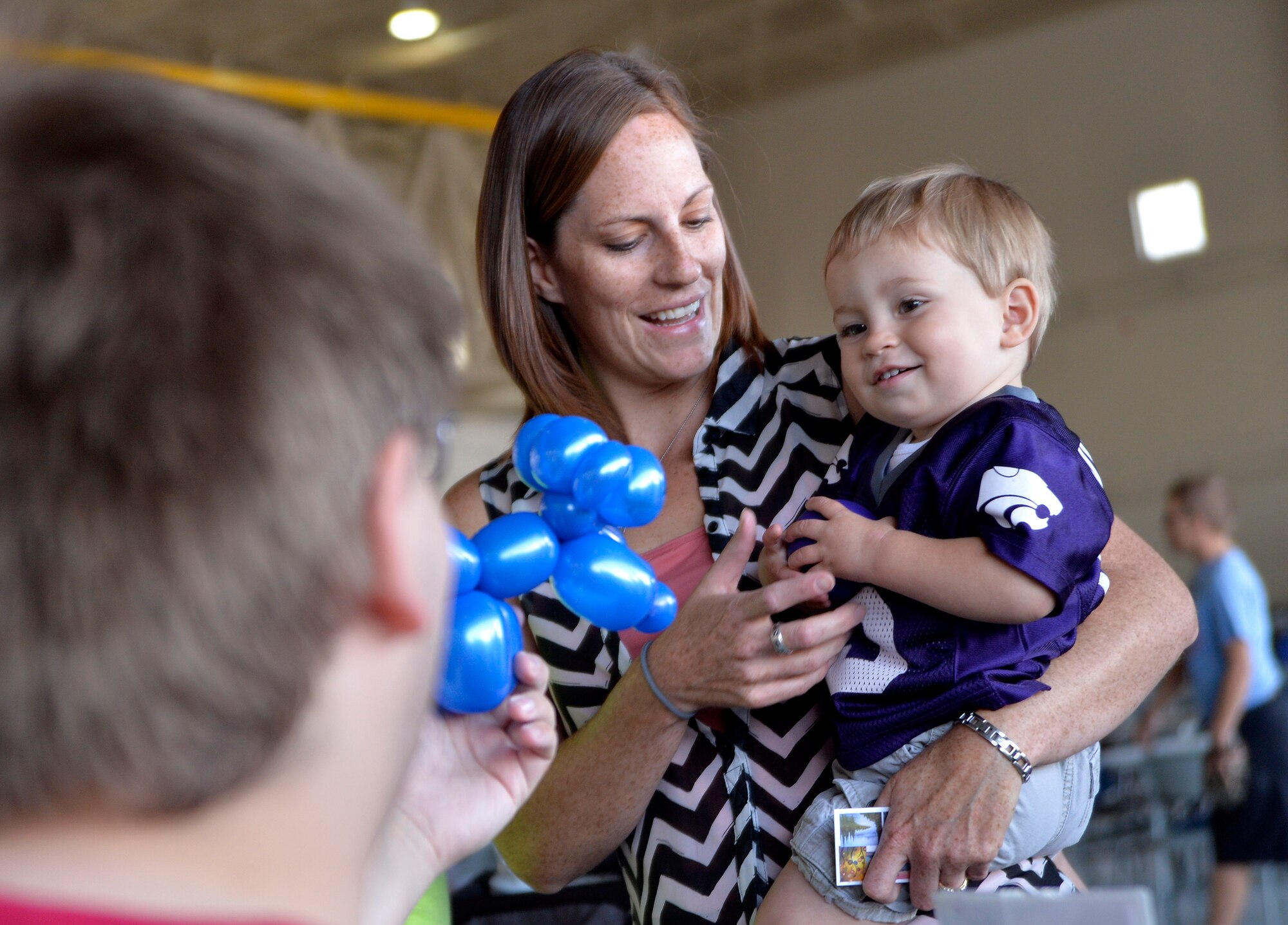 Silas, one, son of Capt. Owen, 15th Reconnaissance Squadron pilot, receives a balloon monkey during a “Take Your Kid to Work Day” event April 23, 2015, at Creech Air Force Base, Nevada. Creech families honored the Month of the Military Child with food, face painting, and a magic show sponsored by the Las Vegas USO. In addition military vehicles and equipment were also on display and included the MQ-1 Predator and MQ-9 Reaper aircraft.  (U.S. Air Force photo by Airman 1st Class Christian Clausen/Released)