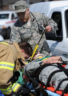 Staff Sgt. Clayton Luker, 28th Medical Operations Squadron medical technician, and Airman 1st Class Robert Martin, 28th Civil Engineer Squadron firefighter, strap Staff Sgt. Jason Prescott, 28th Medical Support Squadron NCO in charge of medical logistics warehouse, onto a wheeled stretcher during a major accident response exercise at Ellsworth Air Force Base, S.D., April 22, 2015. The exercise scenario included a two vehicles collision due to severe weather conditions, testing base personnel’s emergency response actions. (U.S. Air Force photo by Senior Airman Anania Tekurio/Released) 