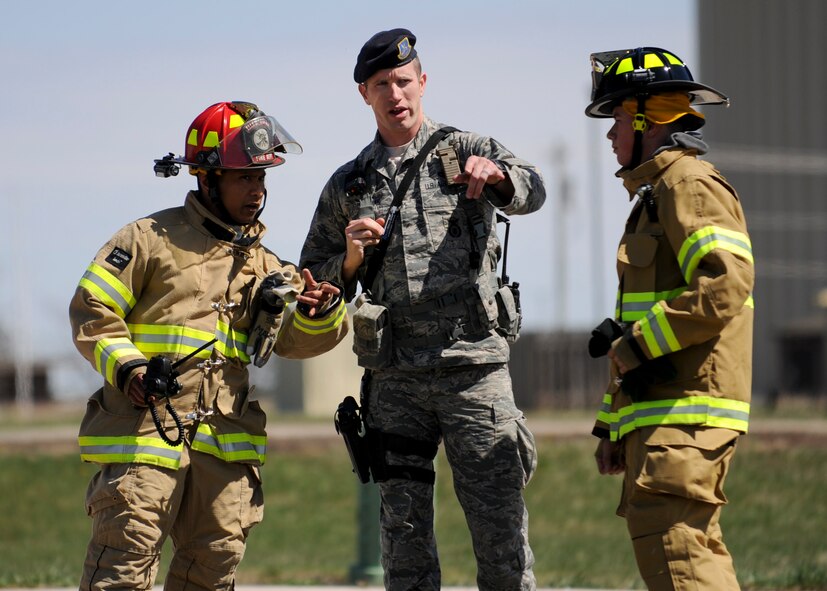 Tech. Sgt. Benjamin Thomas, 28th Security Forces Squadron defender, briefs Tech. Sgt. Roderick Marquez and Airman Jacquob Fitzgerald, 28th Civil Engineer Squadron firefighters, on a simulated accident situation during a major accident response exercise at Ellsworth Air Force Base, S.D., April 22, 2015. While being evaluated, the exercise provided a means for base first responders to apply their training tailored to specific circumstances and conditions. (U.S. Air Force photo by Senior Airman Anania Tekurio/Released)