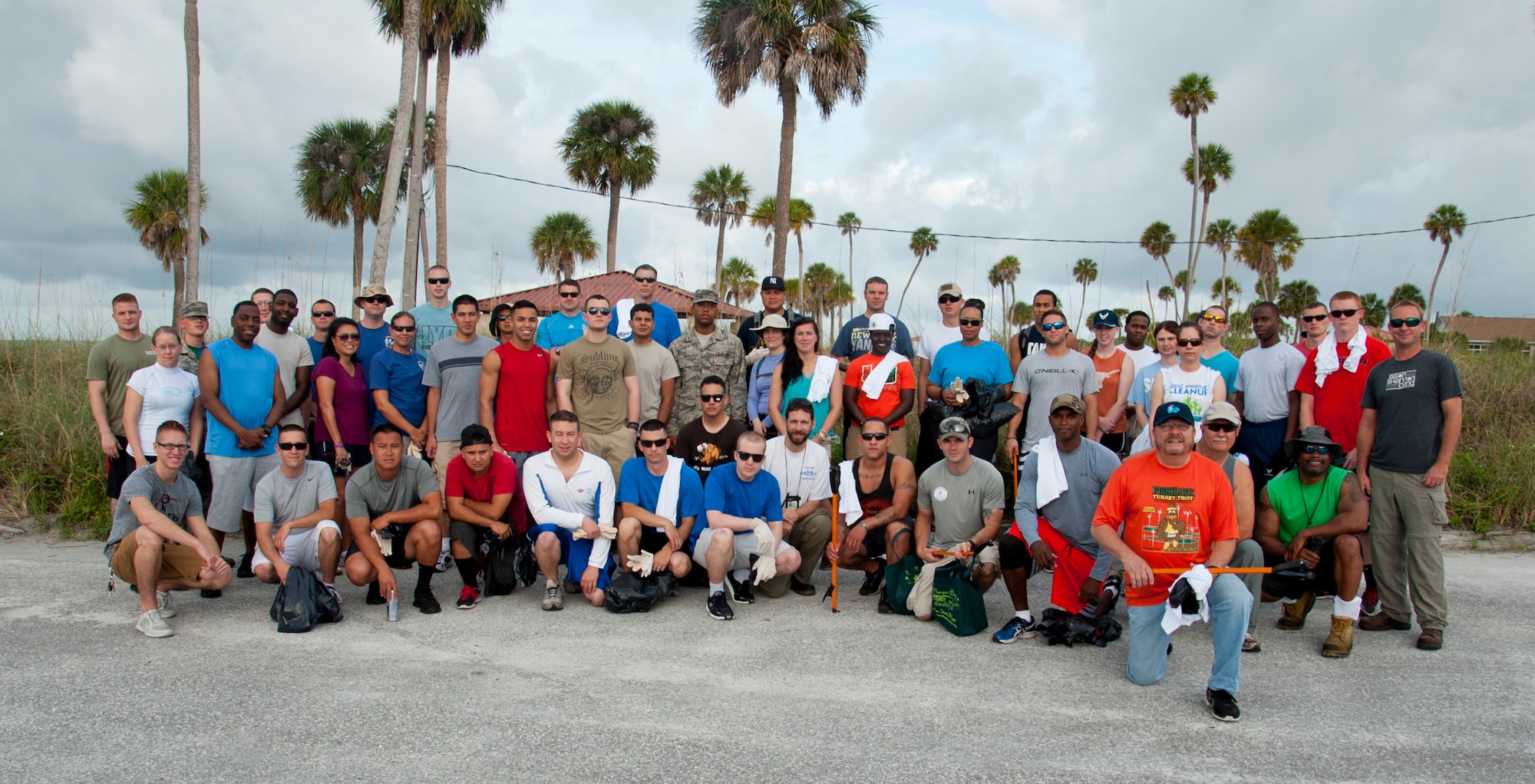 Approximately 50 volunteers from Team MacDill pose for a group photo before tackling the shoreline for the Coastal Clean-up at MacDill Air Force Base, Fla., April 24, 2015. Volunteers were broken up into four groups to clean-up approximately three miles of shoreline from the Thermal Image Radar facility near Eagle Park to the western end of the base beach. (U.S. Air Force photo by Senior Airman Jenay Randolph/Released) 