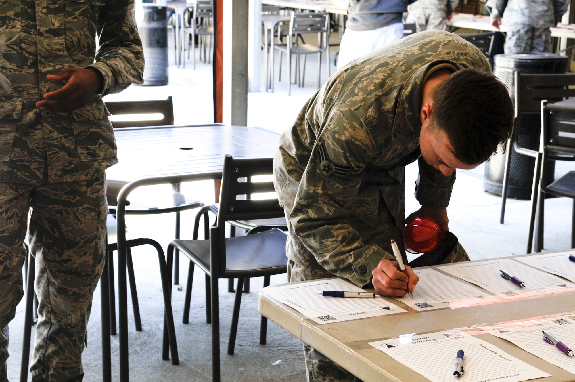 Senior Airman Michael Leigh-Gibson, 11th Civil Engineer Squadron structural journeyman, signs up for an activity at the Community Commons at Joint Base Andrews, Md., April 24, 2015, during the National Capital Region Round Up. The event included food, entertainment, and more than 200 sign-up sheets for different groups, hobbies, and events. (U.S. Air Force photo by Senior Airman Mariah Haddenham/Released)