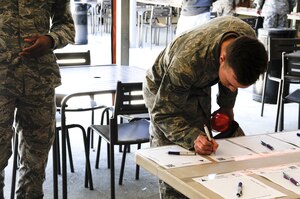 Senior Airman Michael Leigh-Gibson, 11th Civil Engineer Squadron structural journeyman, signs up for an activity at the Community Commons at Joint Base Andrews, Md., April 24, 2015, during the National Capital Region Round Up. The event included food, entertainment, and more than 200 sign-up sheets for different groups, hobbies, and events. (U.S. Air Force photo by Senior Airman Mariah Haddenham/Released)