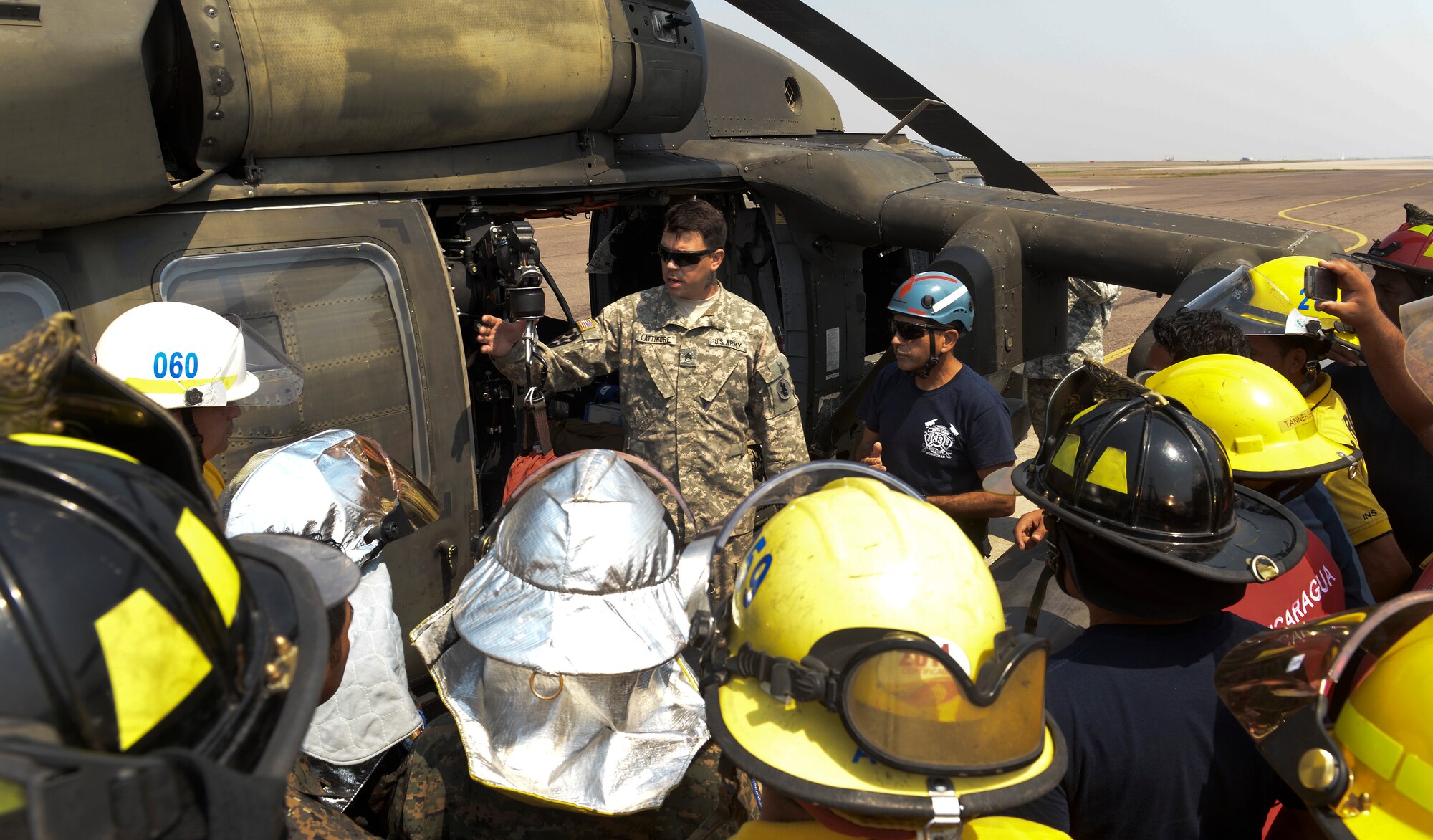 Staff Sgt. Zach Lattimore, a 1-228 Aviation Regiment flight paramedic, instructs firefighters from throughout Central America how to use vital emergency rescue equipment aboard a HH-60 Blackhawk April 23, 2015, at Soto Cano Air Base, Honduras. Thirty-nine firefighters from six of the seven CENTAM nations joined their U.S. counterparts for a week-long exercise to build partnership capacity. Participants were also given training on the CH-47 Chinook. (U.S. Air Force photo by Staff Sgt. Jessica Condit)