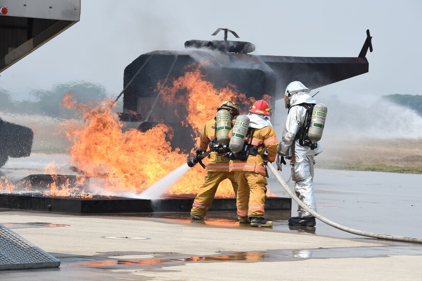 A team of multi-national firefighters spray a simulated helicopter burn during day three of a week-long Central America Sharing Mutual Operations Knowledge and Experience exercise, April 22, 2015, at Soto Cano Air Base. The exercise enhanced participants’ ability to work together in defeating shared challenges. (Photo by Martin Chahin) 
