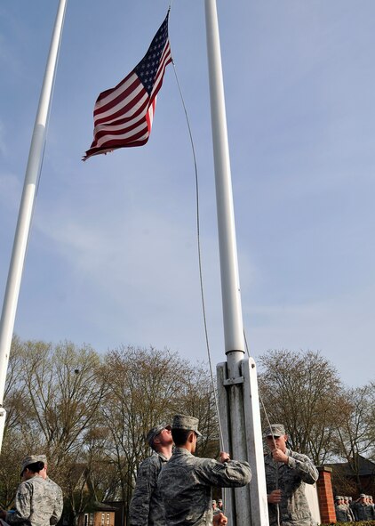 RAF Mildenhall base honor guard Airmen lower the American flag during a monthly retreat ceremony April 24, 2015, at RAF Mildenhall, England. Retreat is a ceremony symbolizing the end of the duty day as well as paying respect to the flags. (U.S. Air Force photo by Airman 1st Class Kyla Gifford/Released)