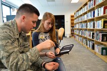 Jessica Narvaez, a library aide at the Laughlin Library, shows 2nd Lt. Brendan Boyd, a member of the 47th Student Squadron who is awaiting pilot training, how to operate the library's new AERO eReaders. The library was one of 19 Air Force libraries that each received 10 of the readers as part of a test program. The readers are preloaded with 200 titles in categories like science fiction, classics, business, history and books from the Chief of Staff’s Reading List.(U.S. Air Force photo by Joel Langton)