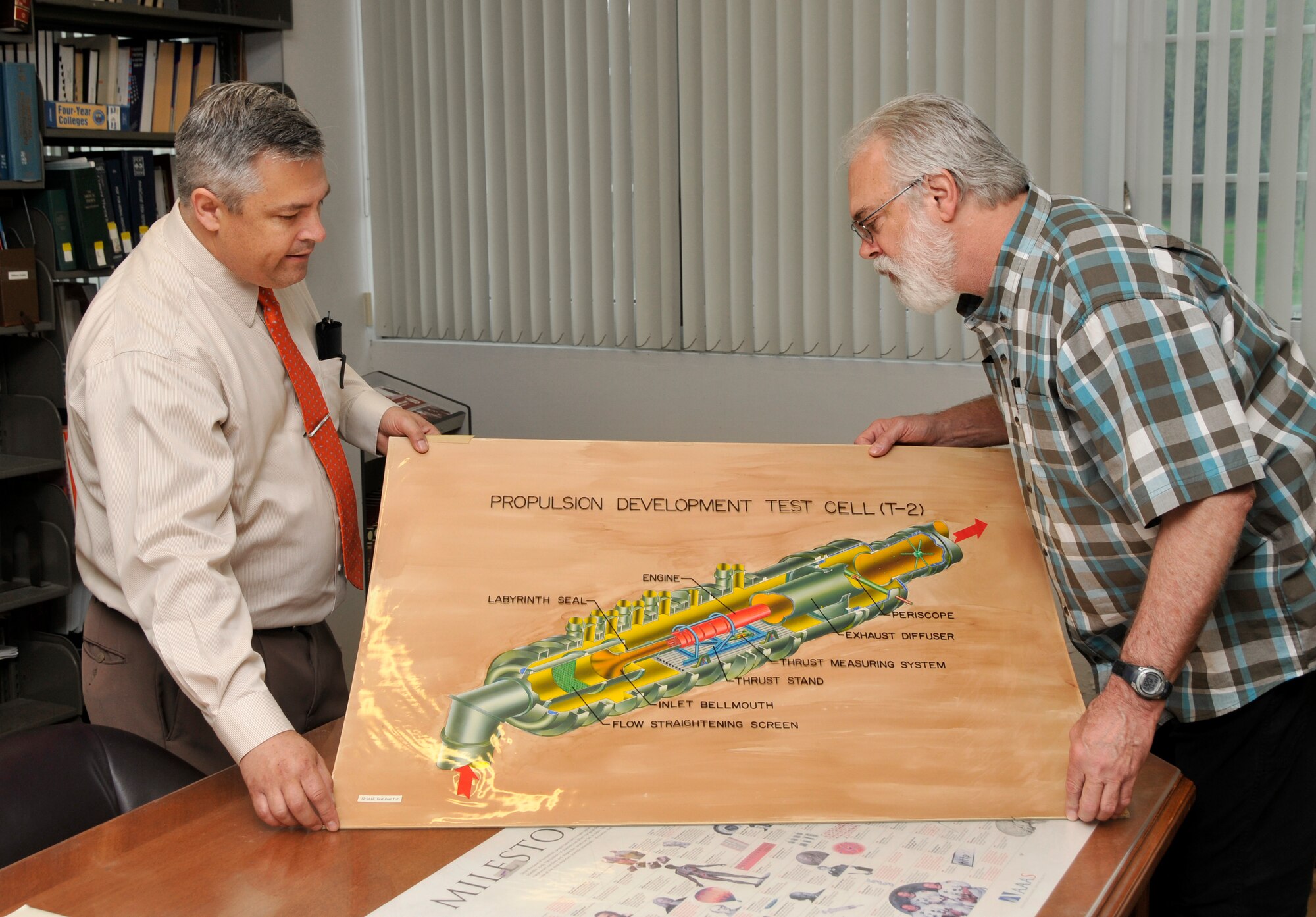 AEDC Historian Chris Rumley (left) shows a propulsion test cell drawing from his archives to AEDC Photographer Rick Goodfriend. The drawing is one of 100 prints for display in the halls of the Administration and Engineering (A&E) building. Goodfriend digitally restored drawings, which are currently displayed in the A&E building, to their original luster. (Photo by Jacqueline Cowan)