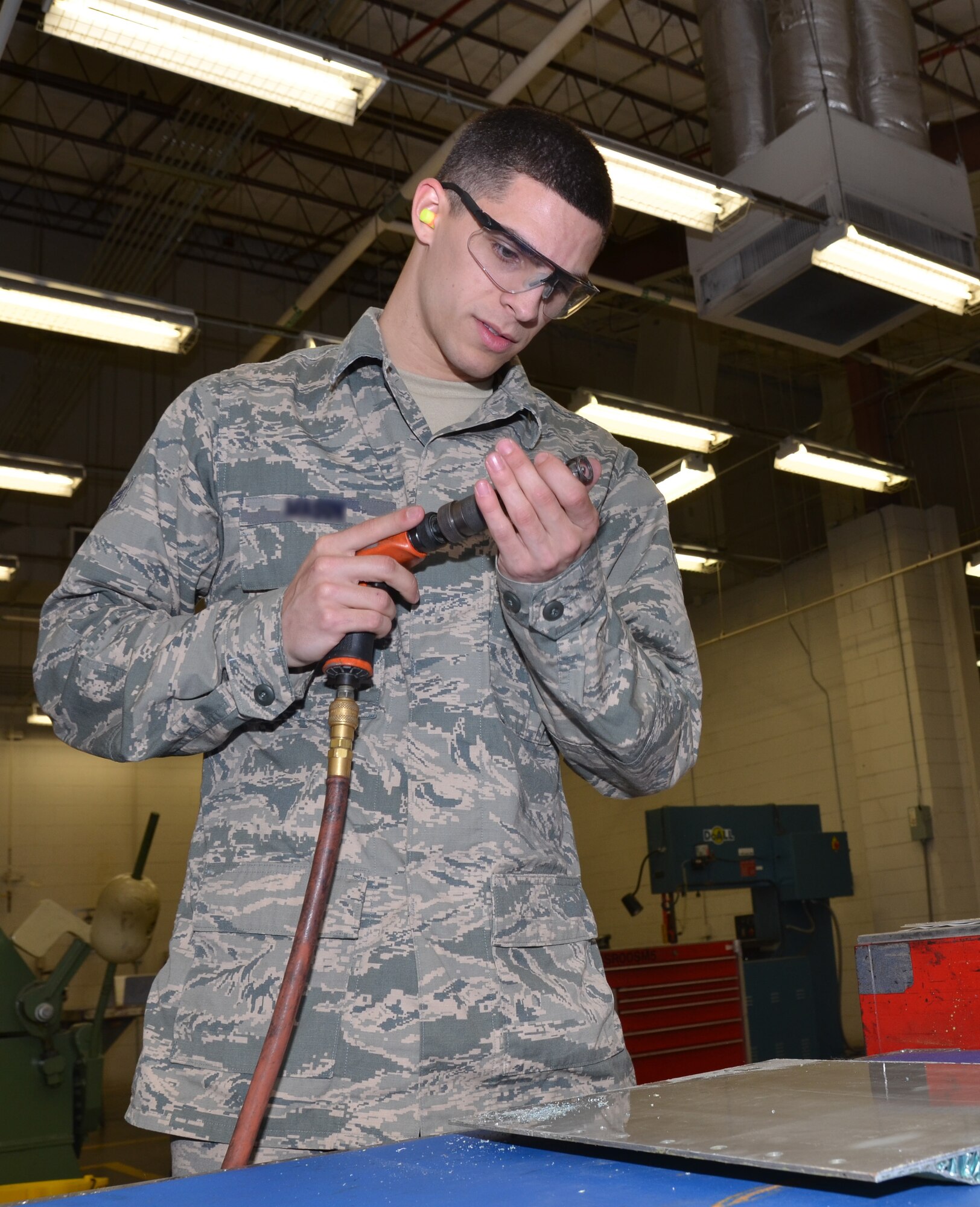 A U.S. Air Force 116th Air Control Wing aircraft structural mechanic, Georgia Air National Guard, adjusts a drill bit he's using to drill countersinks into an aircraft panel, April 20, 2015. The senior airman was recently named 2014 Outstanding Airman of the Year for both the wing and the Georgia Air National Guard. (U.S. Air National Guard photo by Tech. Sgt. Julie Parker/Released)(Names have been blurred/withheld for security purposes)