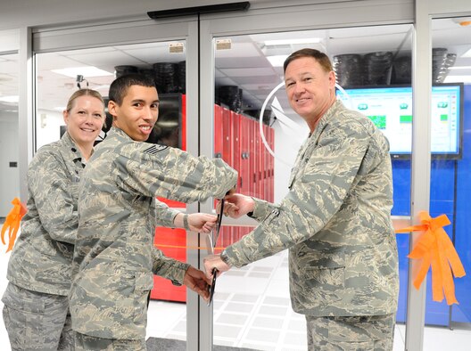 (Right to left) Air Force District of Washington Commander Maj. Gen. Darryl Burke, Staff Sgt. Julian Smith, and Lt. Col. Pamella Zane cut a ribbon officially opening the Shared Computing Environment at Joint Base Andrews, Md., April 24, 2015. The SCE architecture at Joint Base Andrews will reduce the hardware footprint and increase the support capacity to from 75,000 users to more than 200,000 users along the Eastern United States. Rogers is the 844th Communications Group chief technology officer. Smith is the 744th Communications Squadron NCO in charge of the SCE. Zane is the 744th CS commander. (U.S. Air Force photo/Master Sgt. Tammie Moore)