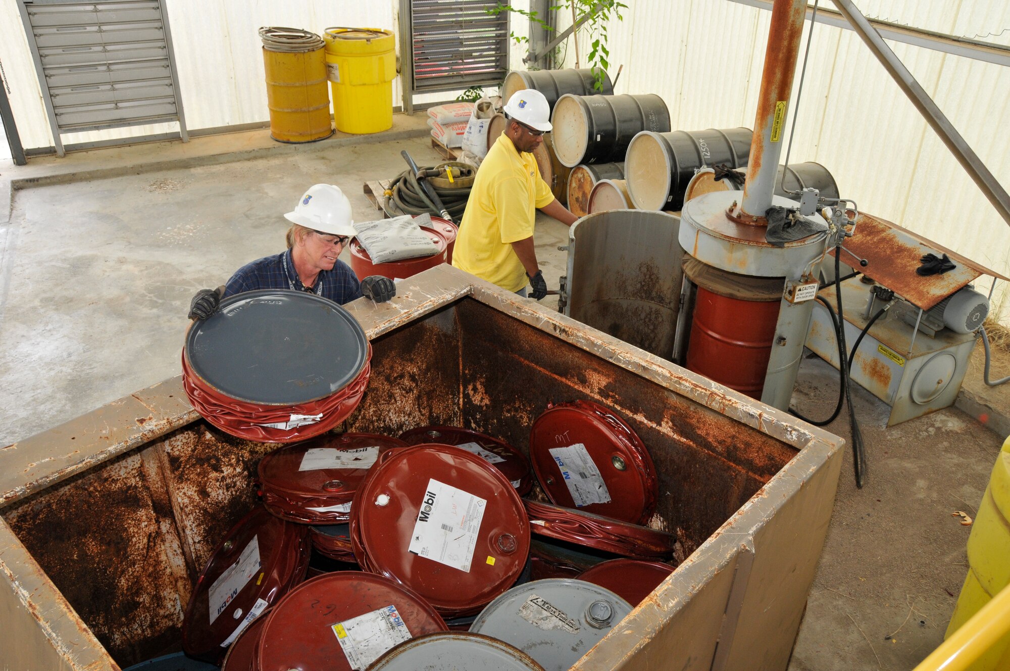 Doug Richards and Charles Wilkerson, with the AEDC Services Recycling Program crush steel drums for recycling at the Complex processing center. (Photo by Rick Goodfriend)