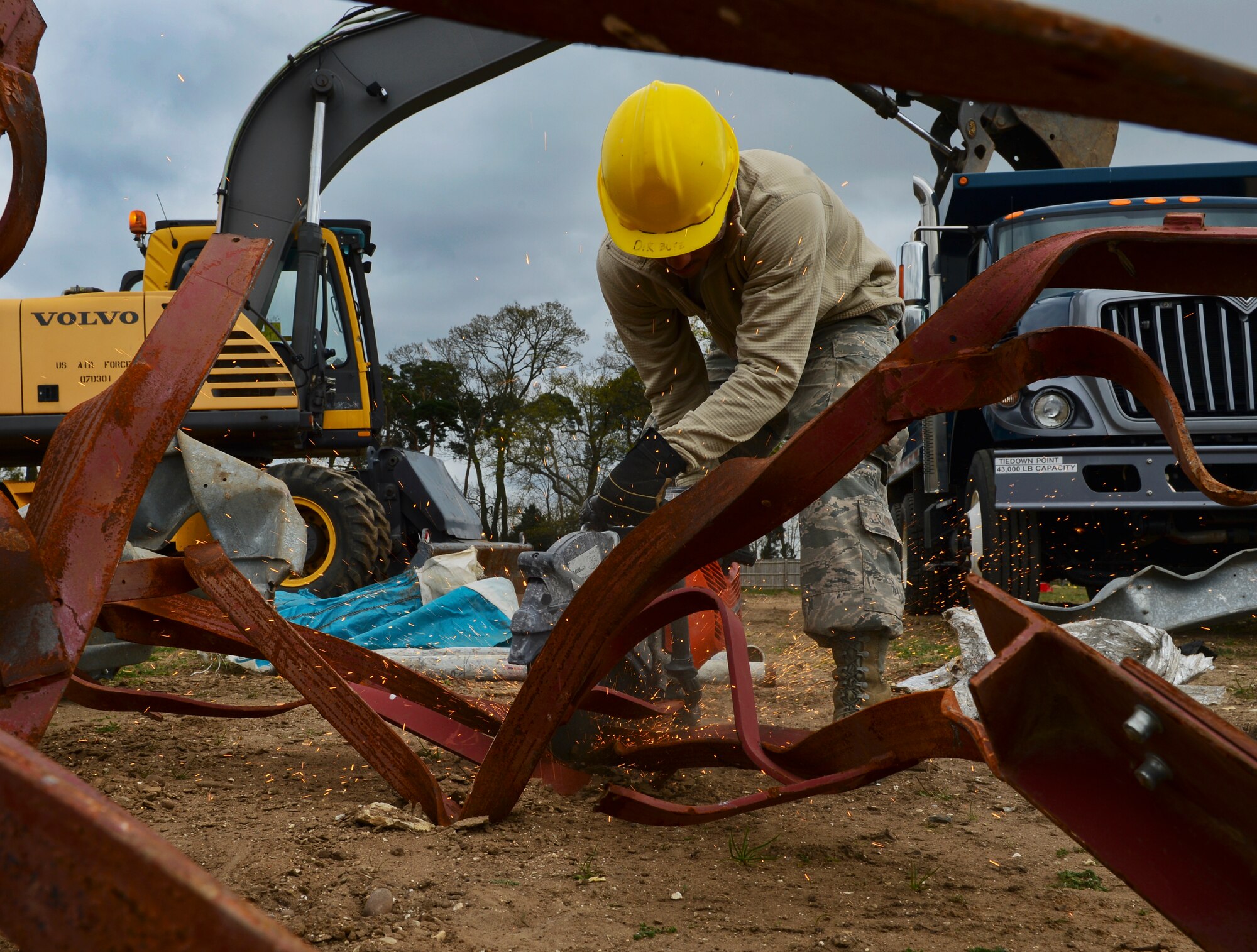 Airman Aaron Matedne, 48th Civil Engineer Squadron heavy equipment operator, cuts metal at Royal Air Force Lakenheath, England, April 22, 2015. After the metal is cut down, transferred to a recycling facilitation. (U.S. Air Force photo by Airman 1st Class Dawn M. Weber/Released)
