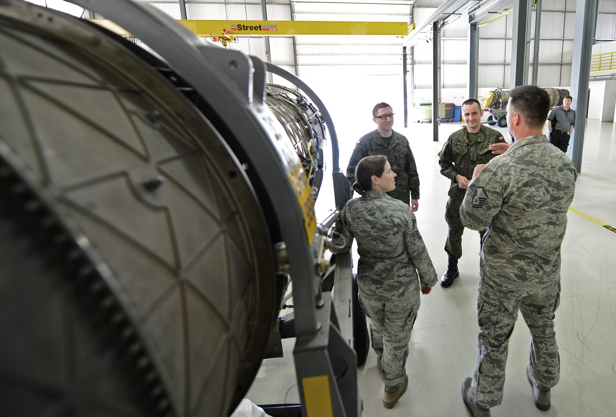 U.S. Air Force Senior Master Sgt. Christine Mahler, 48th Component Maintenance Squadron propulsion flight chief, and Master Sgt. Scott Fitzgerald, 48th CMS propulsion flight superintendent, explain the engine induction process with Polish air force Capt. Rafal Kolasa, 31st Air Base propulsion chief, and 2nd Lt. Michal Miller, 31st AB propulsion section chief, at Royal Air Force Lakenheath, England, April 23, 2015. The Polish airmen visited from Poznan-Krzesiny Air Base to learn how the Liberty Wing operates and manages an engine overhaul facility. (U.S. Air Force photo by Airman 1st Class Erin R. Babis/Released)