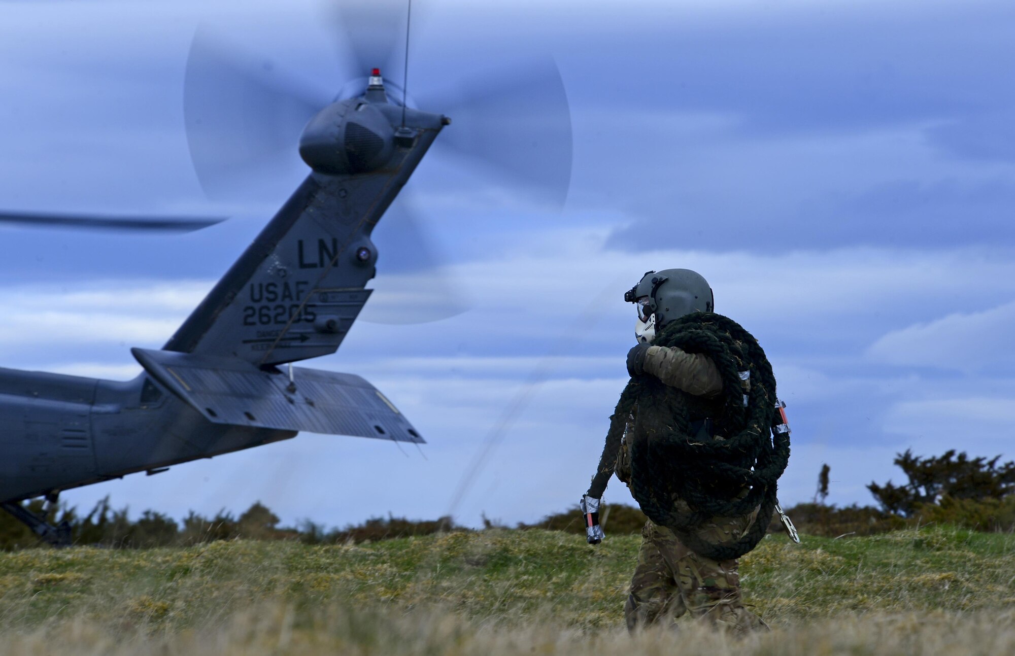 A special missions aviator assigned to Royal Air Force Lakenheath's 56th Rescue Squadron carries a fast rope toward an HH-60G Pave Hawk during Joint Warrior 15-1 in Scotland, April 21, 2015. The exercise enhanced rescue readiness, by replicating scenarios pararescuemen may encounter during real-world operations. (U.S. Air Force photo by Senior Airman Erin O'Shea/Released)