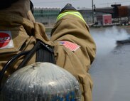 A firefighter from Osan Air Base, Republic of Korea, points to a still burning fire inside the fire pit during training April 22, 2015, at the U.S. Army Garrison Humphreys', ROK. The training, hosted by firefighters from Humphreys' assisted the Osan firefighters with annual training requirements necessary to maintain safety for the more than 10,000 service members, dependents and civilians who reside in and around Osan AB. (U.S. Air Force photo by Staff Sgt. Benjamin Sutton/Released)