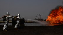 Two firefighters from Osan Air Base, Republic of Korea, perform extinguishing techniques on a pit fire during training April 22, 2015, at the U.S. Army Garrison Humphreys', ROK. The training, hosted by firefighters from Humphreys' assisted the Osan firefighters with annual training requirements. (U.S. Air Force photo by Staff Sgt. Benjamin Sutton/Released)