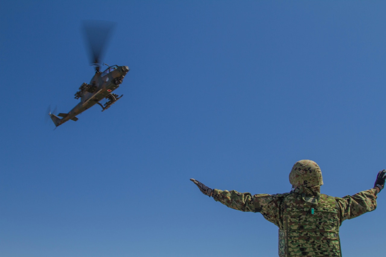 A Japan Ground Self-Defense Force member guides a Cobra anti-tank helicopter onto a forward aircraft refueling point at Yakima Training Center, Wash., Sept. 4, 2014. The exercise was part of Operation Rising Thunder, a combined operation between the U.S. Army and Japan Self-Defense Force designed to increase interoperability between the two nations. U.S. Army photo by Sgt. Cody Quinn