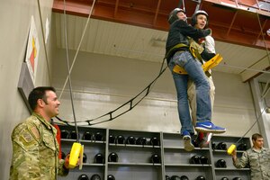 Air Force Junior ROTC students from Charles Francis Adams High School in Clarkston, Wash.,, are hoisted up by Staff Sgt. Ray C-Perez, 22nd Training Squadron Survival, Evasion, Resistance and Escape specialist, during a base wide tour April 22, 2015, at Fairchild Air Force Base, Wash. The hoist machine is used by students to train and practice before going out on the field and getting hoisted up onto the UH-1N Iroquois helicopter. (U.S. Air Force photo/Senior Airman Janelle Patiño)