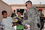 Maj. Edward Michels, 1st Battalion, 178th Field Artillery of the South Carolina Army National Guard, gives two boys a handful of toys during a humanitarian aid drop at Maihan Orphanage in Kabul, Afghanistan Aug. 31, 2010. Michels and several other servicemembers stationed at Camp Phoenix participated in the drop delivering toys, blankets, shoes and clothing.