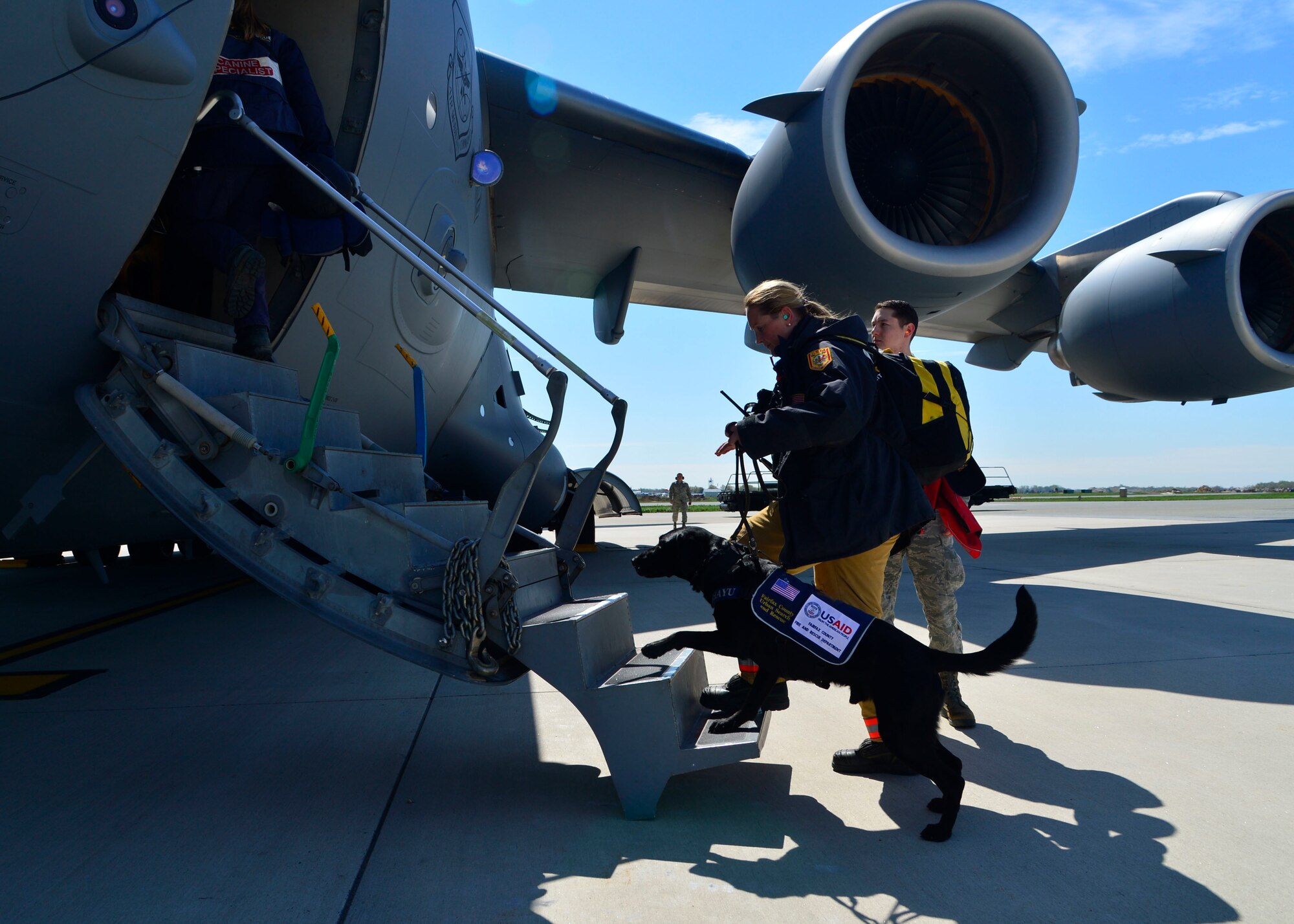 Jennifer Massey, Fairfax County Urban Search and Rescue K-9 search specialist, Fairfax, Va., and her K-9, Phayu, board a U.S. Air Force C-17 Globemaster III at Dover Air Force Base, Del., April 26, 2015. Massey and Phayu are part of a 69-person search and rescue team deploying to Nepal to assist in rescue operations after the country was struck by a 7.8-magnitude earthquake. (U.S. Air Force photo/Airman 1st Class William Johnson)